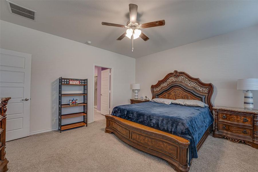 Bedroom featuring ceiling fan, light colored carpet, and ensuite bathroom