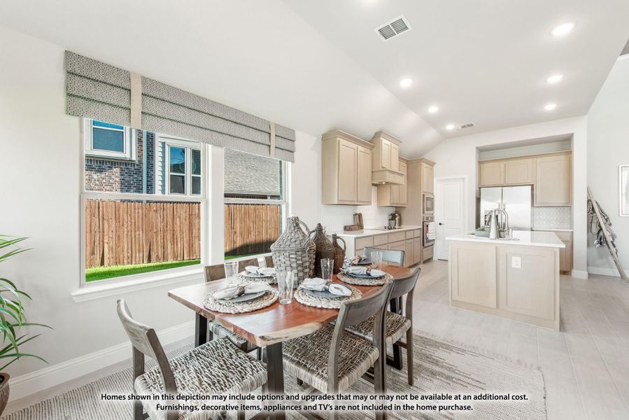 Open dining area with wood table and four chairs, connected to kitchen with beige cabinets and center island