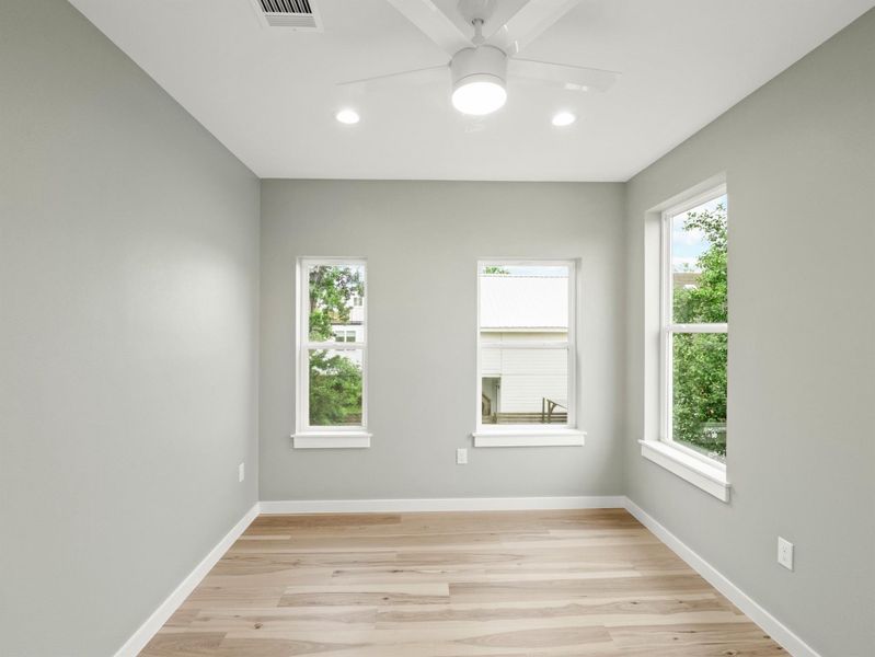 Room featuring wood-finish flooring, light grey walls, and white trim