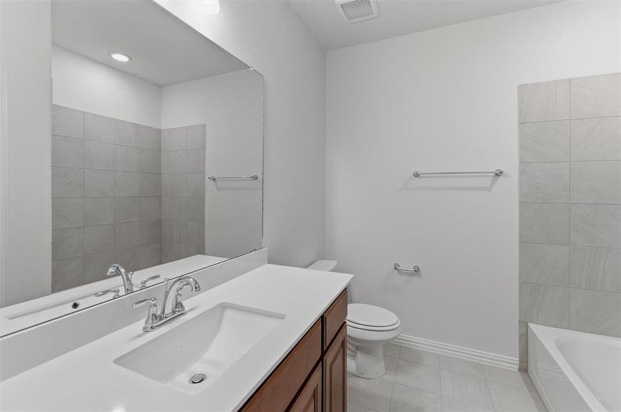 Bathroom featuring a rectangular undermount sink with a chrome faucet, a wood-finish vanity, and a large wall-mounted mirror