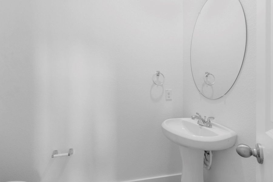 Convenient half bath on the main floor with a pedestal sink and oval mirror, ideal for guests during gatherings. Convenient half bath on the main floor with a pedestal sink and oval mirror, ideal for guests during gatherings.