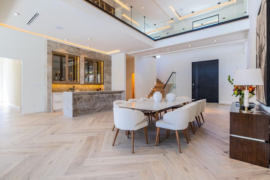 Dining room located adjacent to the wet bar, featuring dramatic double-height ceilings and designed for elevated entertaining. Dining room located adjacent to the wet bar, featuring dramatic double-height ceilings and designed for elevated entertaining.