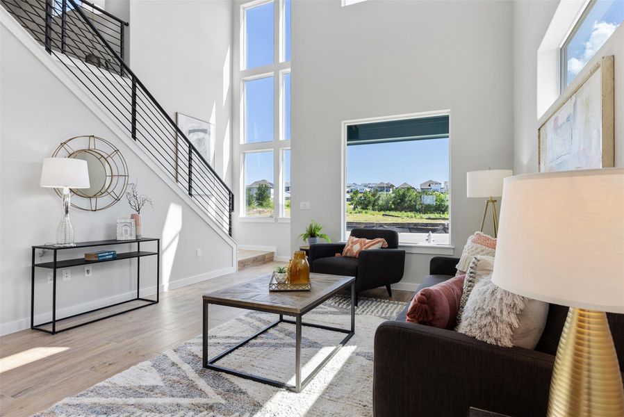 Living room with stairs, healthy amount of natural light, wood finished floors, and a towering ceiling
