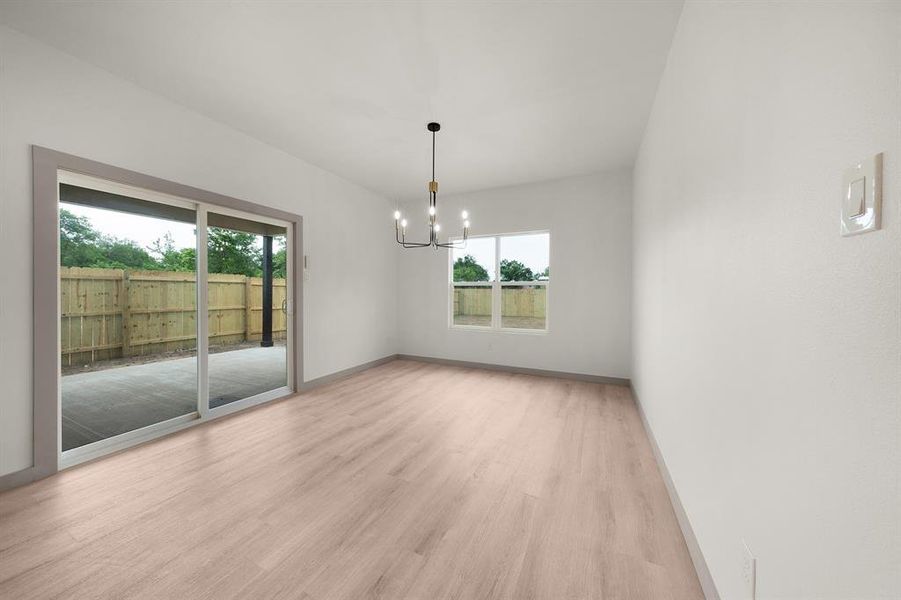Empty room featuring an inviting chandelier, baseboards, plenty of natural light, and light wood-type flooring
