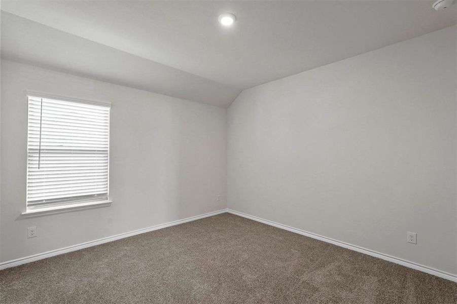 Carpeted spare room with vaulted ceiling