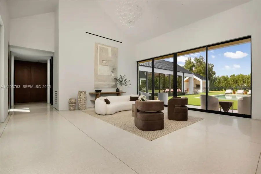 Vaulted ceilings with a contemporary chandelier, expansive multi-panel sliding glass doors, polished stone flooring, and built-in dark wood cabinetry