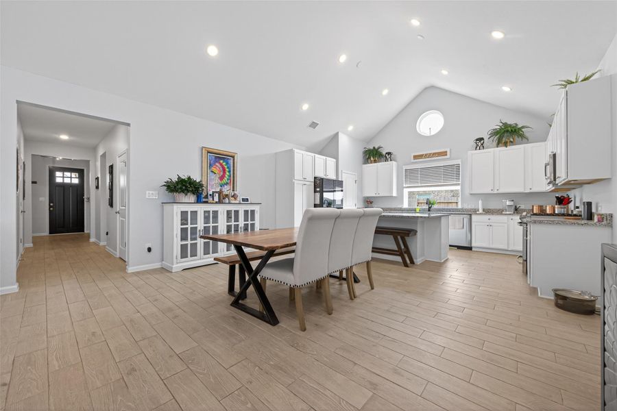 Spacious kitchen and dining space with vaulted ceilings and abundant lighting