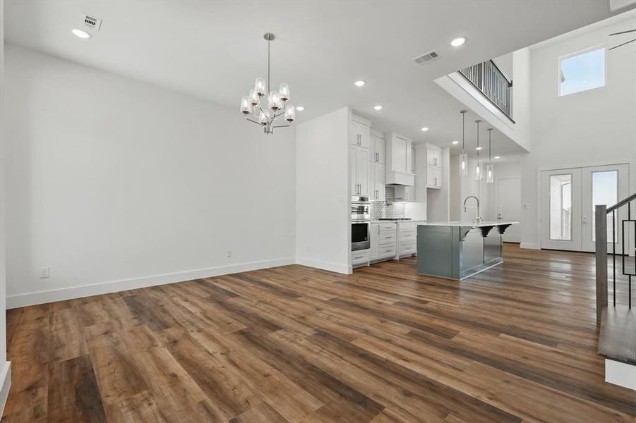 Unfurnished living room with dark wood-type flooring, a healthy amount of sunlight, visible vents, and baseboards