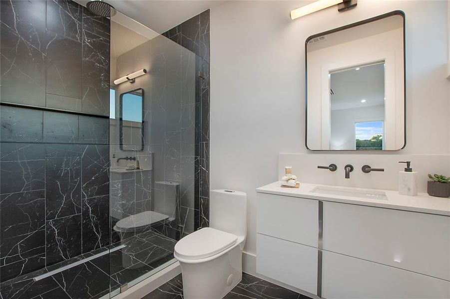 Bathroom with tiled shower, vanity, and toilet