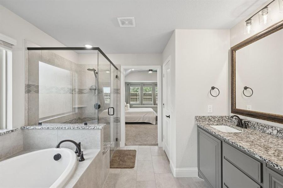 Full bathroom featuring a garden tub, vanity, a shower stall, ceiling fan, and tile patterned floors Full bathroom featuring a garden tub, vanity, a shower stall, ceiling fan, and tile patterned floors