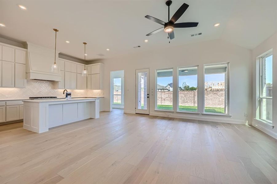 Kitchen featuring light wood-type flooring, white cabinetry, ceiling fan, and a center island with sink