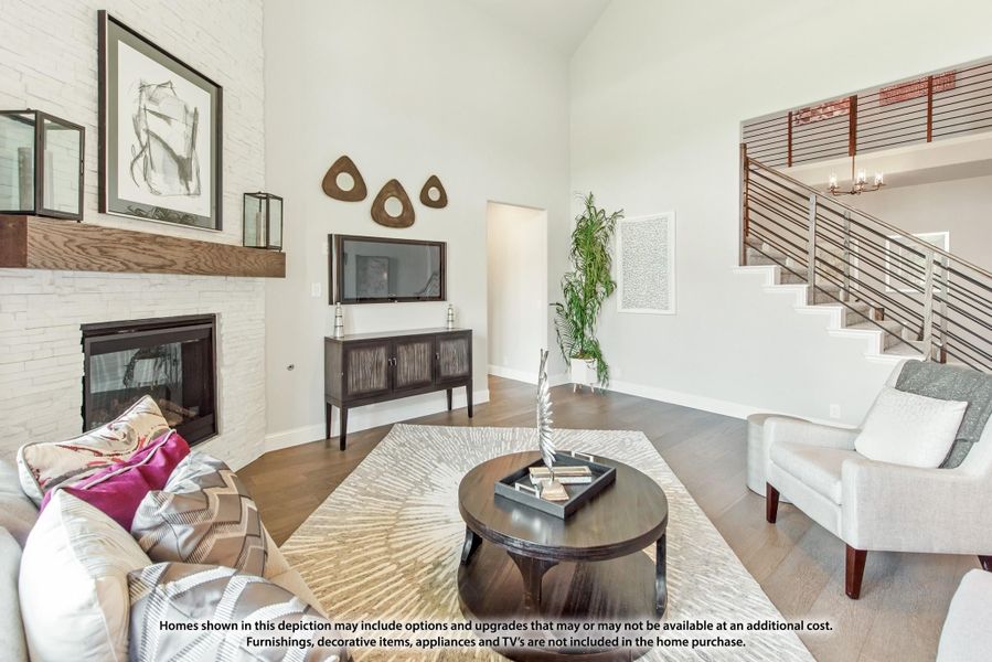Living room with white brick fireplace, high ceilings, hardwood floors, and open staircase with metal railing