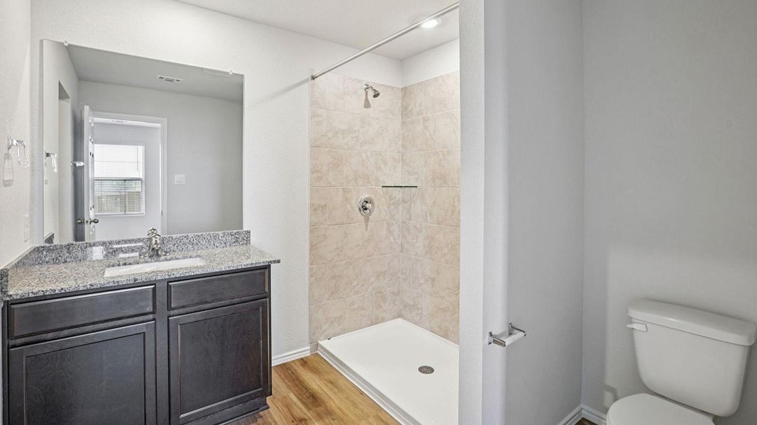 A well-appointed bathroom features a single vanity with granite counters and a spacious standing shower.