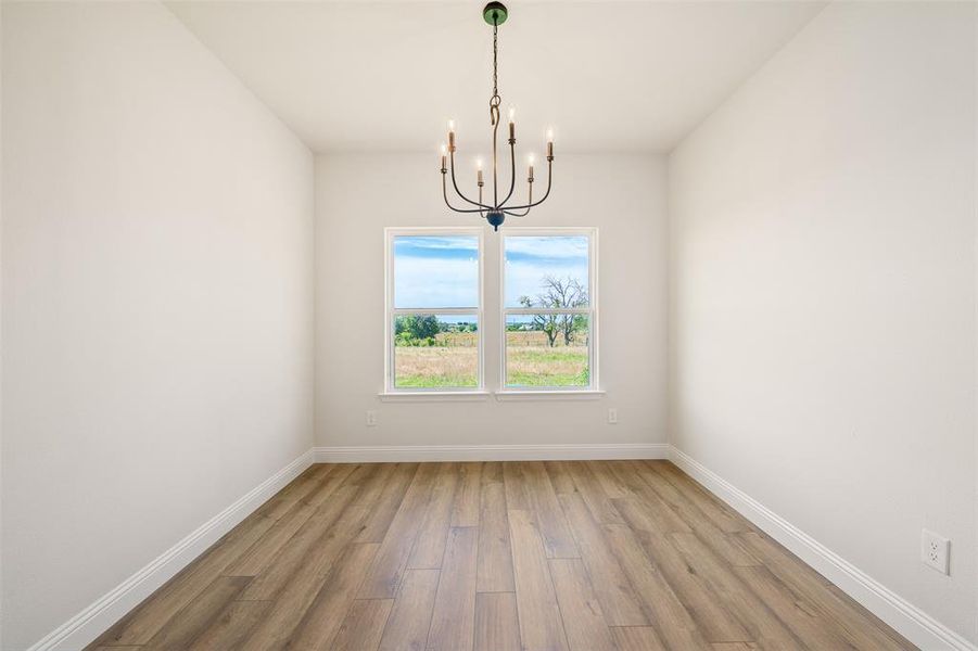 Empty room featuring light wood-style floors and a chandelier