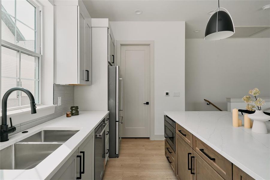 Contemporary kitchen featuring a dual-tone cabinetry scheme, stainless steel appliances, and wood-finish flooring