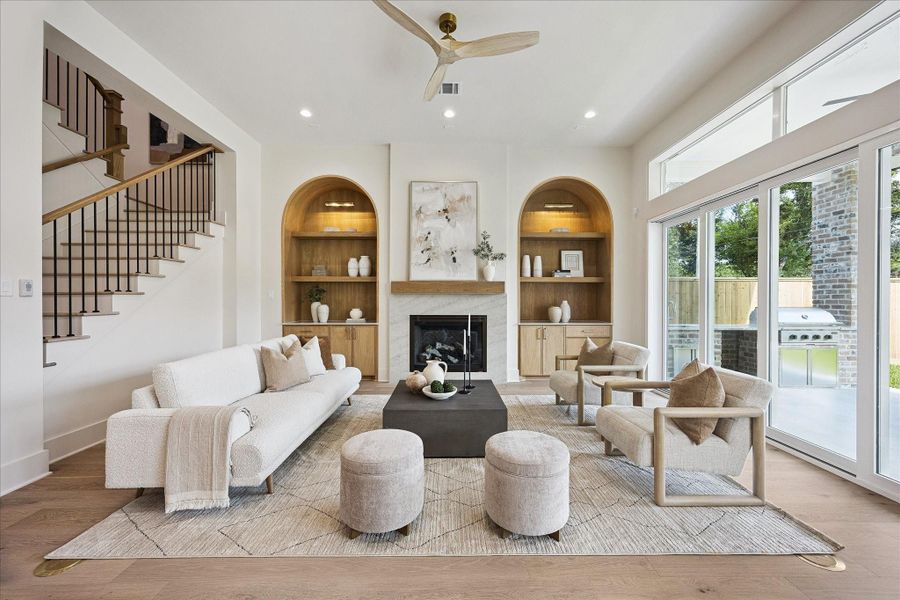 The heart of the home feels both elegant and comfortable, with 12-foot ceilings, a romantic gas log fireplace framed by custom arched white oak built-ins, wide plank engineered white oak flooring and a wall of folding glass doors that fills the room with natural light and extends your living space outdoors.
