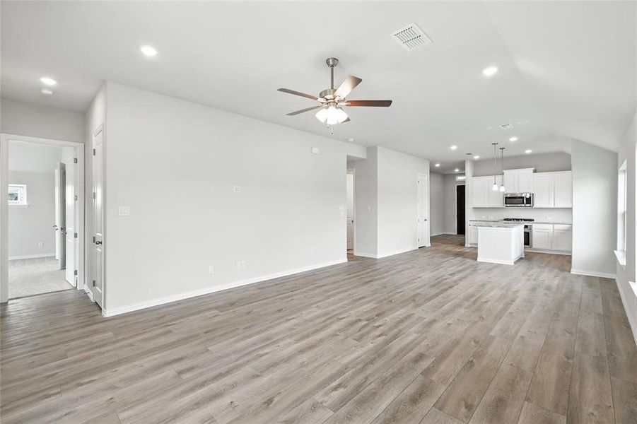 Unfurnished living room featuring ceiling fan, vaulted ceiling, light wood finished floors, and recessed lighting