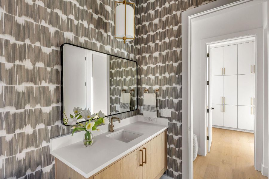 Bar area with light wood finish cabinetry, light countertops, tile walls, and light wood finished floors