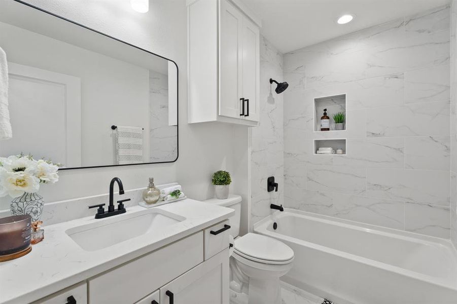 Full bathroom featuring vanity, tiled shower / bath combo, and toilet Full bathroom featuring vanity, tiled shower / bath combo, and toilet