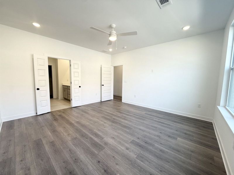 Unfurnished bedroom with a ceiling fan, connected bathroom, dark wood-style flooring, and recessed lighting