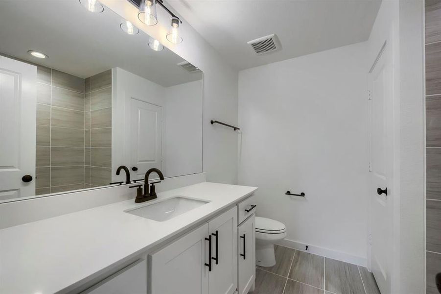 Contemporary bathroom with a white vanity, integrated sink, and dark bronze-finish fixtures Contemporary bathroom with a white vanity, integrated sink, and dark bronze-finish fixtures