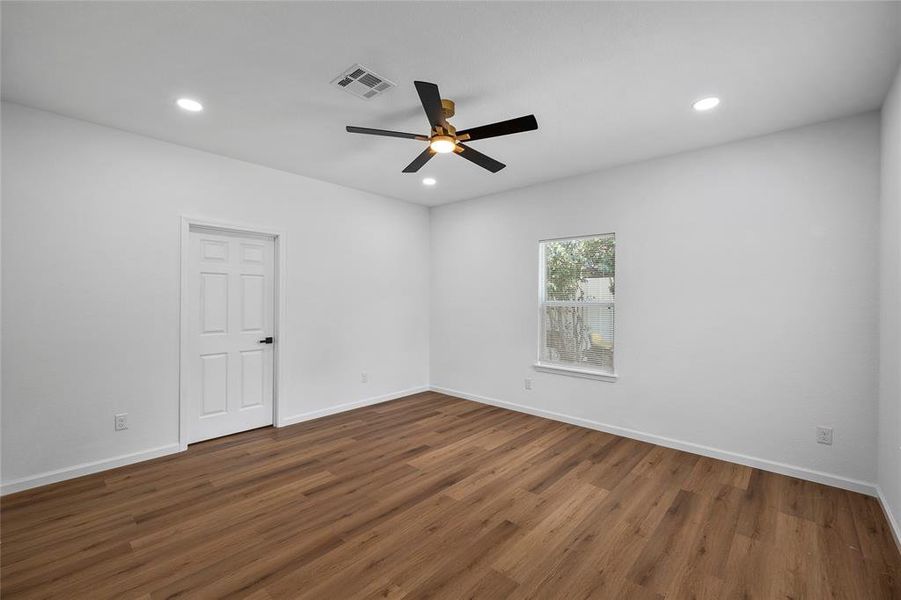 Spacious room featuring wood-finish flooring, recessed lighting, and a contemporary ceiling fan Spacious room featuring wood-finish flooring, recessed lighting, and a contemporary ceiling fan