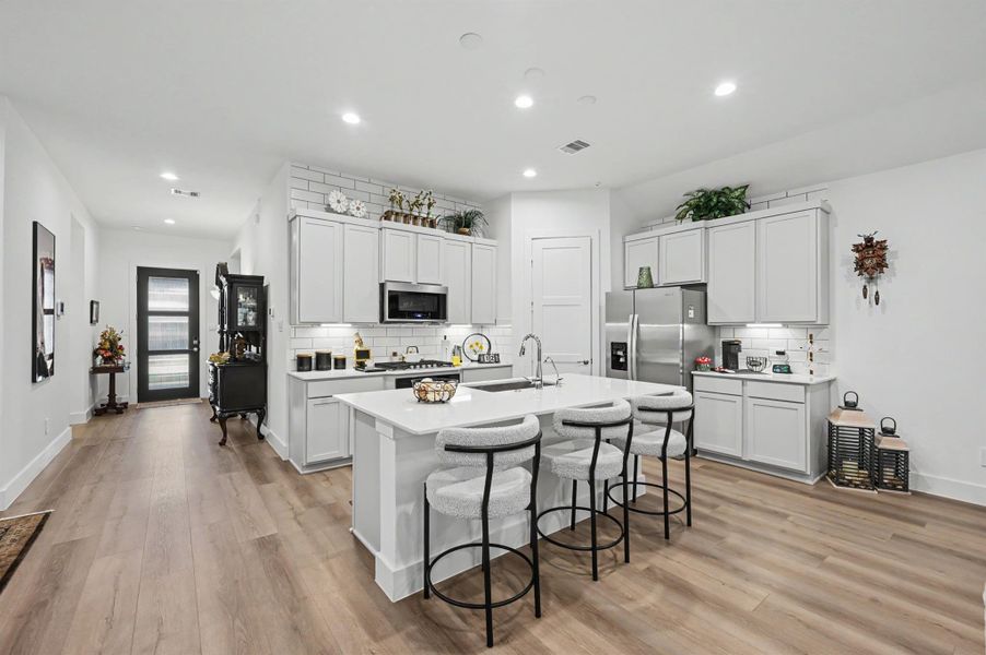 The kitchen features silestone countertops, gas range cooktop, large stainless-steel sink and the subway backsplash is built up to the ceiling. The kitchen features silestone countertops, gas range cooktop, large stainless-steel sink and the subway backsplash is built up to the ceiling.