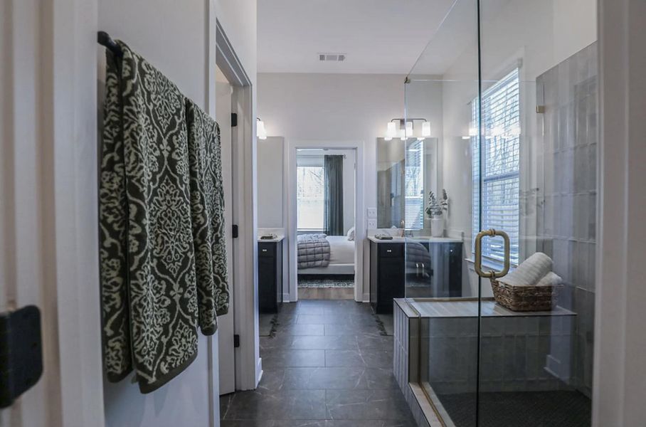Spacious bathroom featuring a glass-enclosed shower with a built-in bench, dark tile flooring, and a single vanity with a white countertop