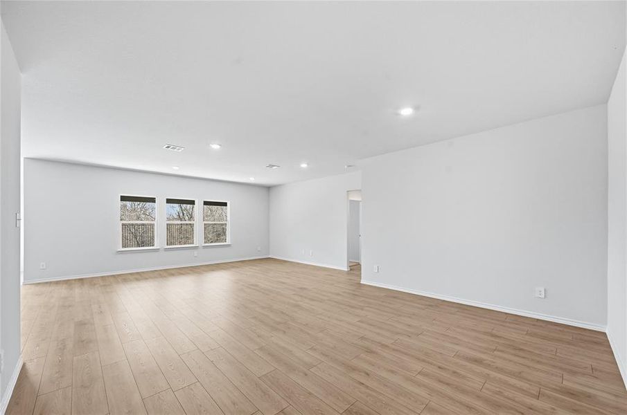 Expansive room featuring wood-finish flooring, recessed lighting, and a row of three windows Expansive room featuring wood-finish flooring, recessed lighting, and a row of three windows