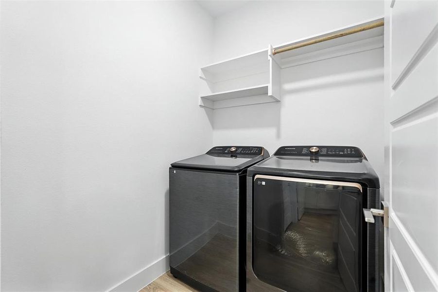 Laundry area featuring washing machine and clothes dryer and light wood finished floors found downstairs