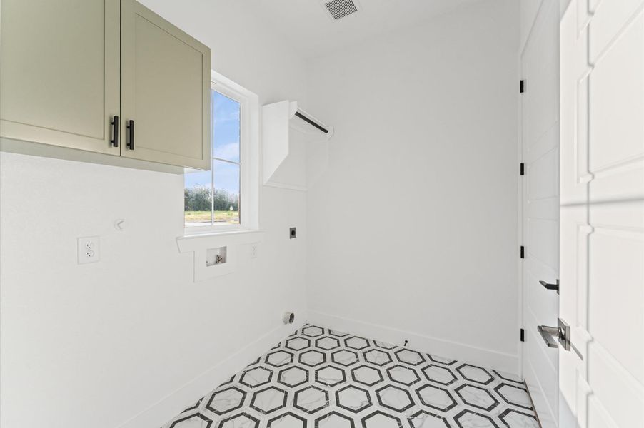 Spacious laundry room featuring upper cabinets for organized storage and utility.Upgraded flooring adds a sleek, durable finish to this well-designed, functional space. Spacious laundry room featuring upper cabinets for organized storage and utility.Upgraded flooring adds a sleek, durable finish to this well-designed, functional space.