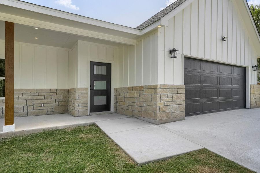 A well-maintained facade features board and batten siding with a complementary stone wainscoting.