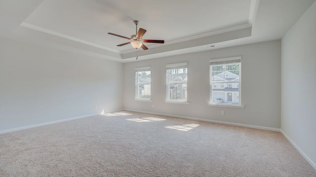 Spacious Ridgewood primary suite with tray ceiling, carpet flooring, and neutral modern finishes at Bowers Farm.