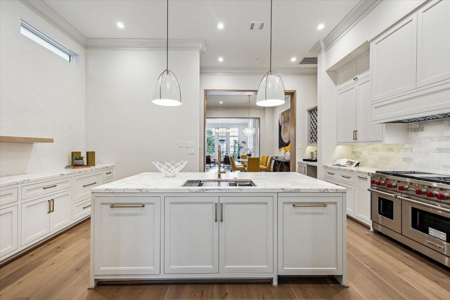 The kitchen's center island features marble countertop with signature edge profile, Ruvati workstation, and a Bosch dishwasher with disappearing cabinet panel. The tumbled marble backsplash and inset, custom-built cabinetry complete the look. The kitchen's center island features marble countertop with signature edge profile, Ruvati workstation, and a Bosch dishwasher with disappearing cabinet panel. The tumbled marble backsplash and inset, custom-built cabinetry complete the look.