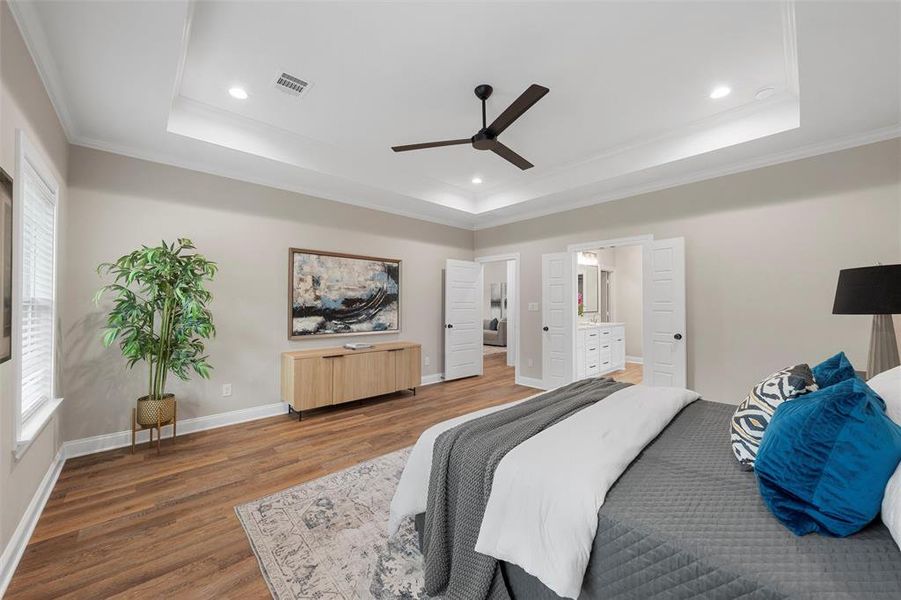 Bedroom featuring visible vents, ornamental molding, wood finished floors, and a tray ceiling