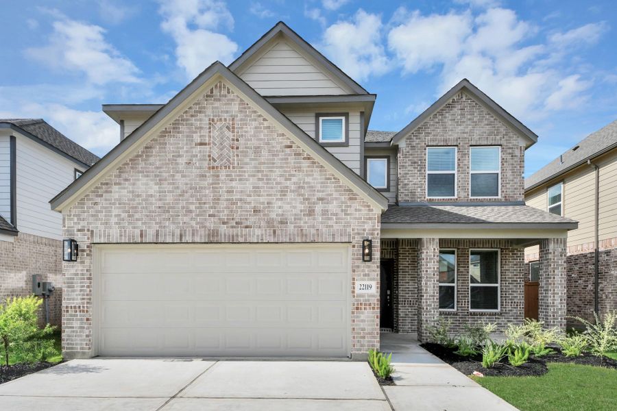 Behold a lush landscape, impeccably maintained yard, and a premium elevation adorned with captivating brick and stone features.