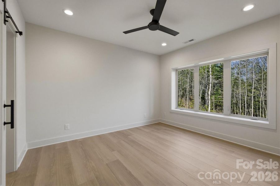 On the left side of the lower level is found Bedroom Suite #4. This bedroom features a Minka-Aire ceiling fan and a "view". Notice that there is a stylish barn-door that leads into an ensuite bathroom for this bedroom. On the left side of the lower level is found Bedroom Suite #4. This bedroom features a Minka-Aire ceiling fan and a "view". Notice that there is a stylish barn-door that leads into an ensuite bathroom for this bedroom.