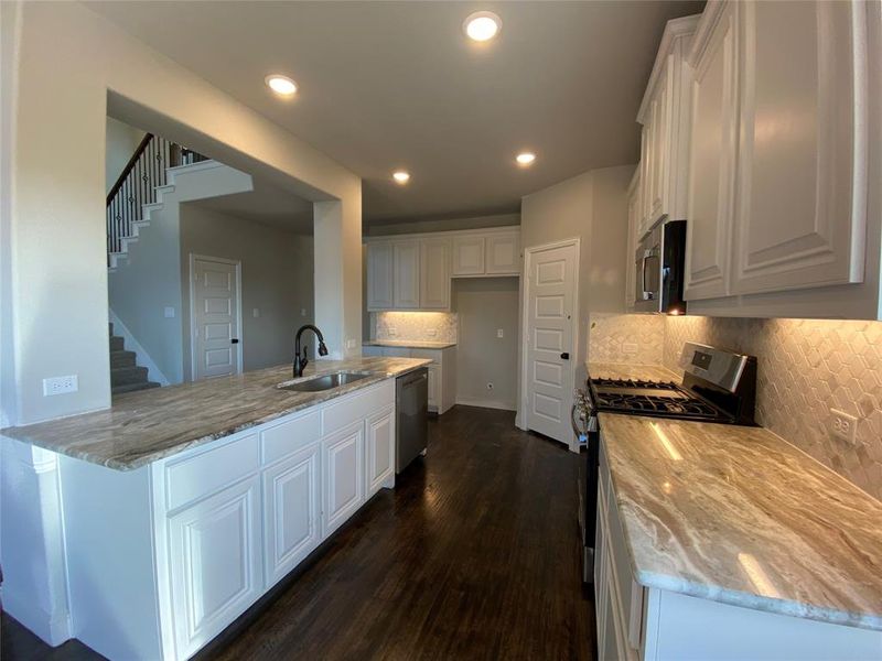 Kitchen offers custom Fantasy Brown granite, white cabinets, and rich Ebony hardwood floors