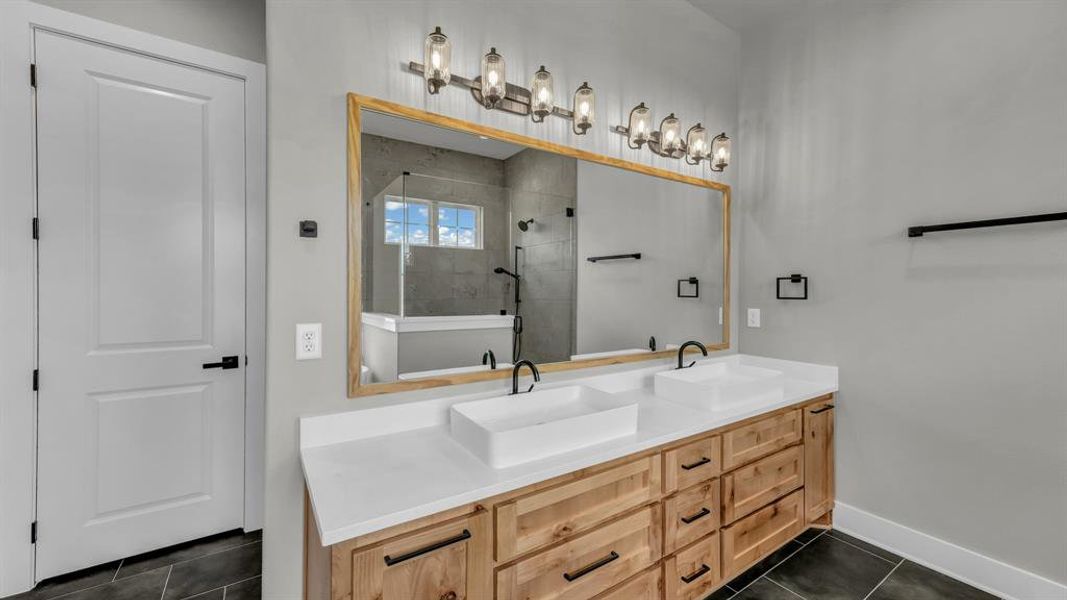 Double vanity with natural wood-finish cabinetry, solid surface countertops, and vessel sinks