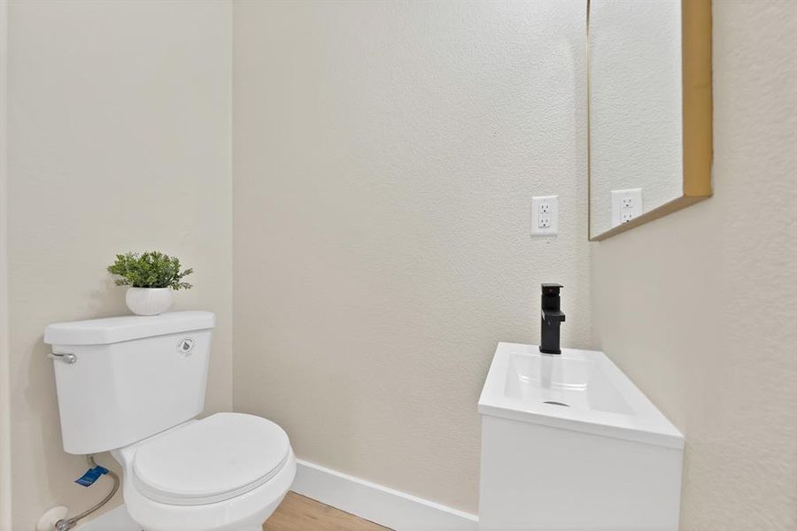Half bathroom with vanity, wood finished floors, and a textured wall