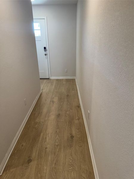 Hallway featuring wood finished floors and a textured wall