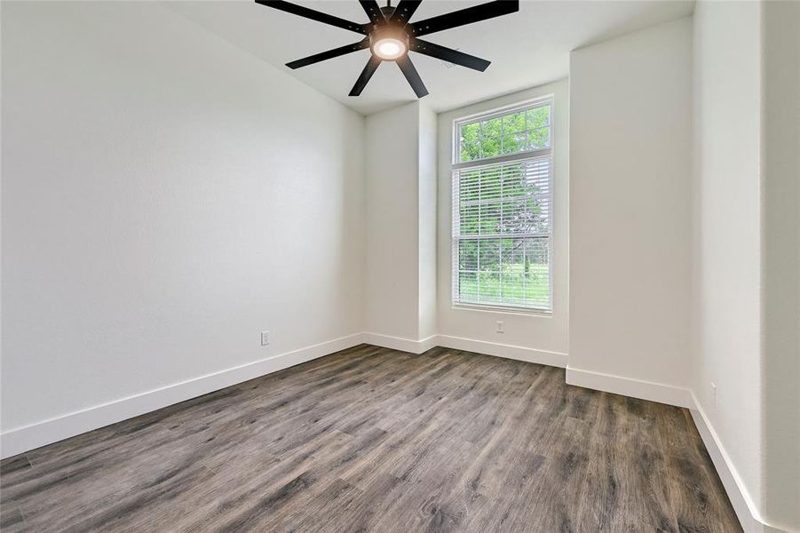 Empty room featuring baseboards, ceiling fan, and dark wood-type flooring