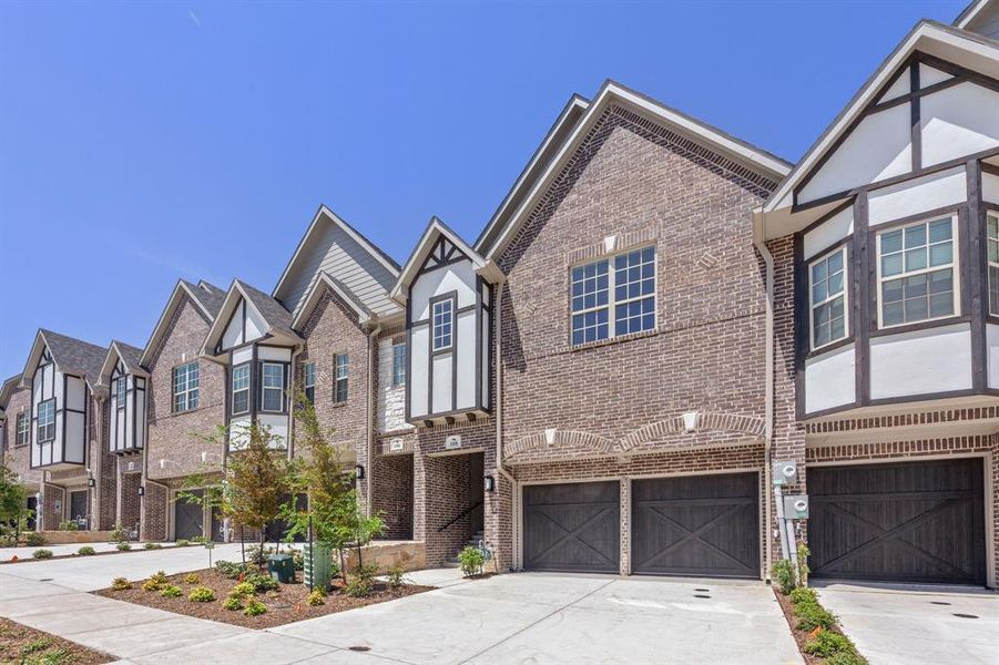 Tudor-style house with driveway, brick siding, an attached garage, and a residential view Tudor-style house with driveway, brick siding, an attached garage, and a residential view