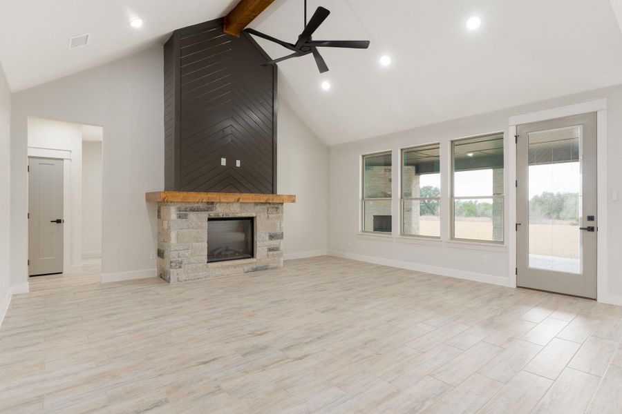 Unfurnished living room featuring beam ceiling, a ceiling fan, a fireplace, high vaulted ceiling, and recessed lighting