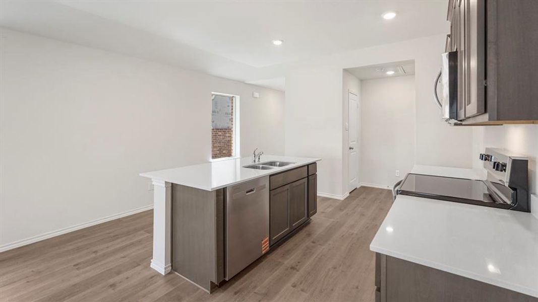 Modern kitchen featuring an island with a double basin sink, stainless steel dishwasher, and white countertops