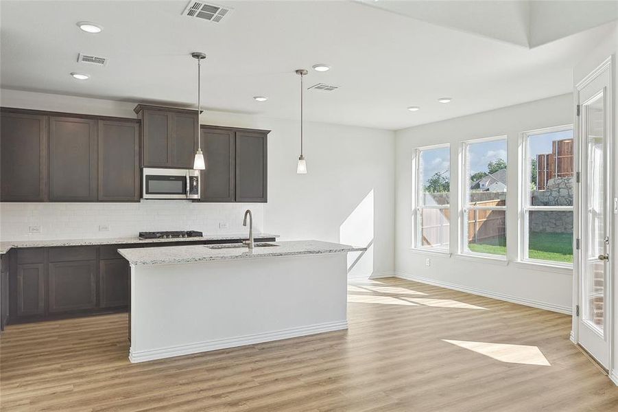 Kitchen with light hardwood / wood-style floors, sink, backsplash, and light stone counters