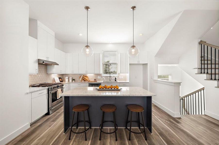 An absolutely stunning kitchen with A huge island , quartz countertops, and designer backsplash.