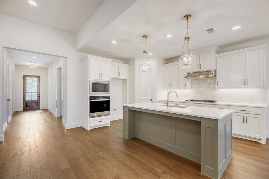 Kitchen featuring a central island with a contrasting base, white countertops, and a built-in sink