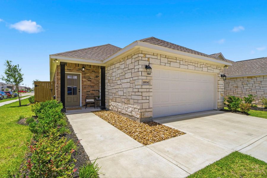 Beautiful stone-and-brick exterior with professional landscaping, a covered front porch, oversized two-car garage, and charming curb appeal, ideally situated on a spacious corner lot in the sought-after master-planned community of Emberly
