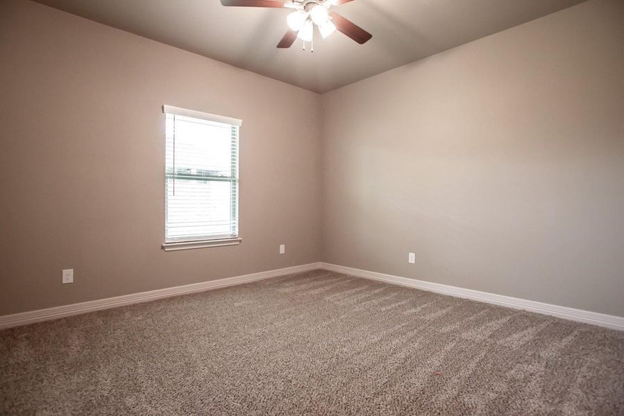Carpeted spare room featuring baseboards and ceiling fan